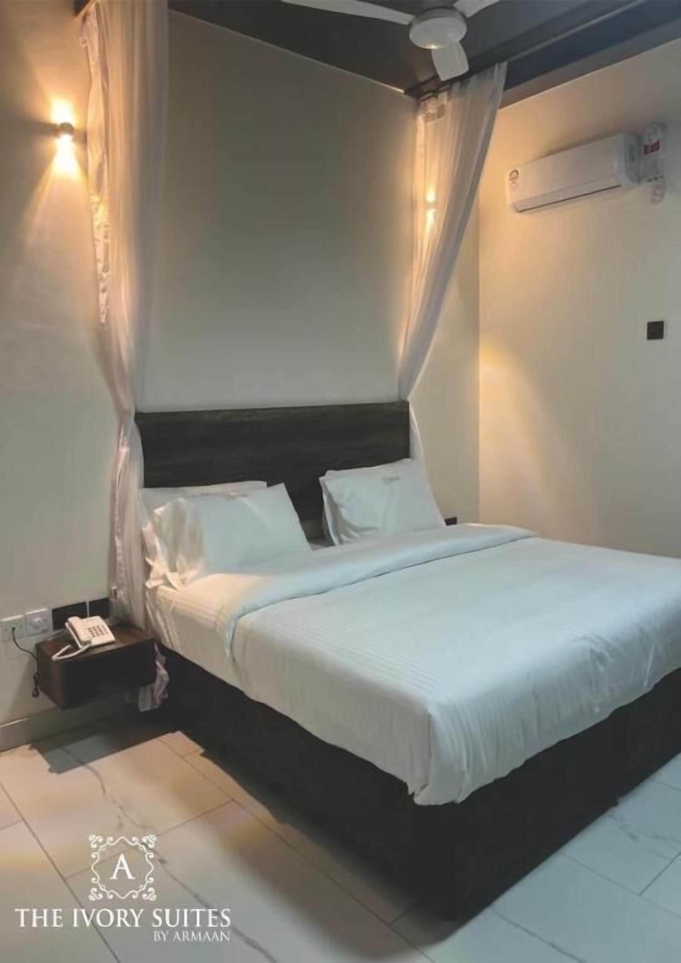 Een slaapkamer met een bed, nachtkastje, telefoon en airconditioning.