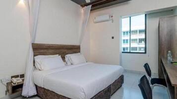Une chambre à coucher avec un lit, un ventilateur de plafond, une fenêtre et un bureau avec une chaise.