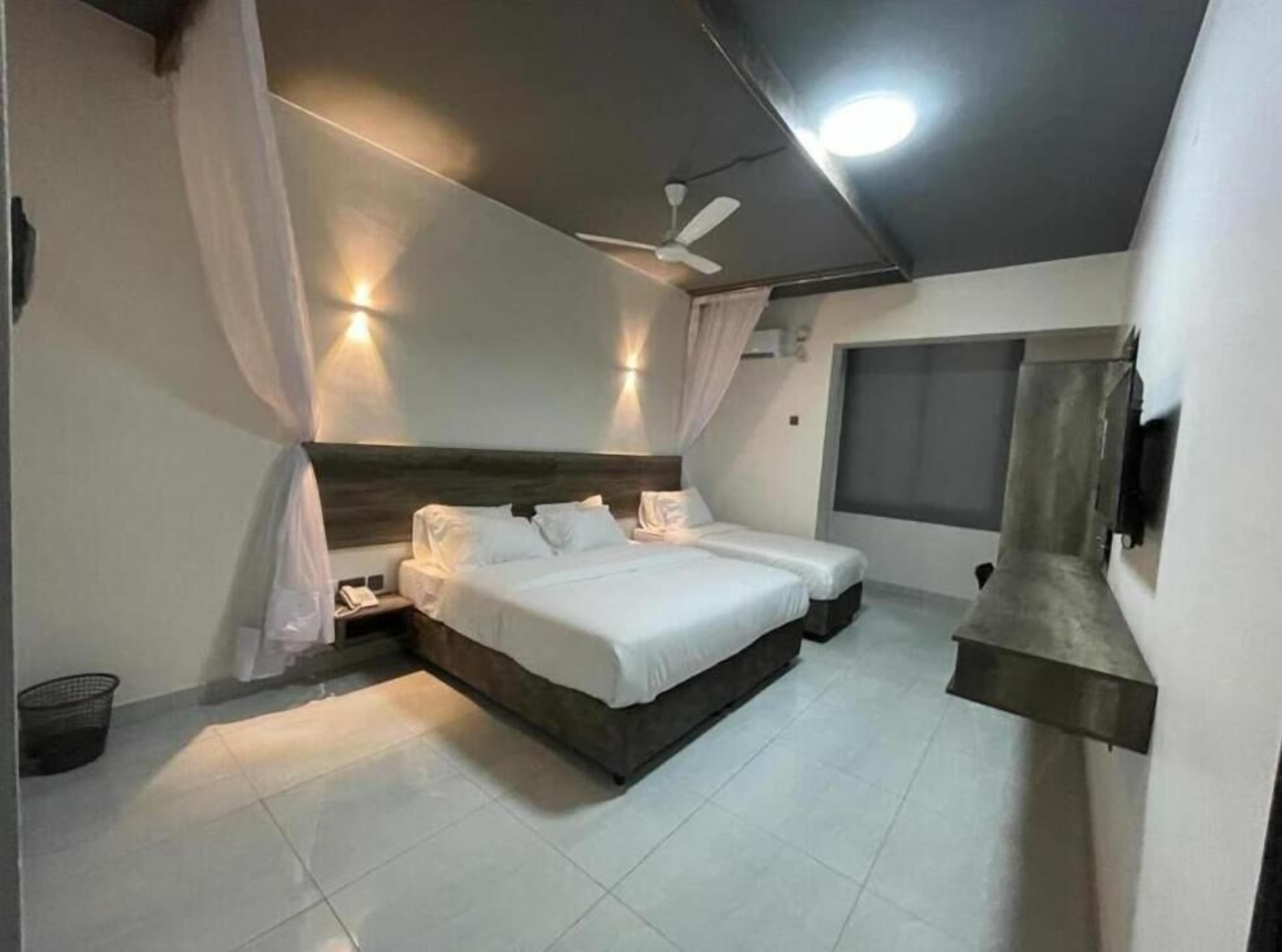 A bedroom with a large bed, a ceiling fan, and a window.