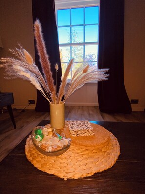 A round woven tray with a glass bowl containing food items, a square woven mat, and a vase with dried plants. - Brylach Steading (Aberlour)