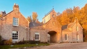 Un bâtiment en pierre doté d’une arche centrale, de nombreuses fenêtres et d’une petite tour surmontée d’une horloge.
