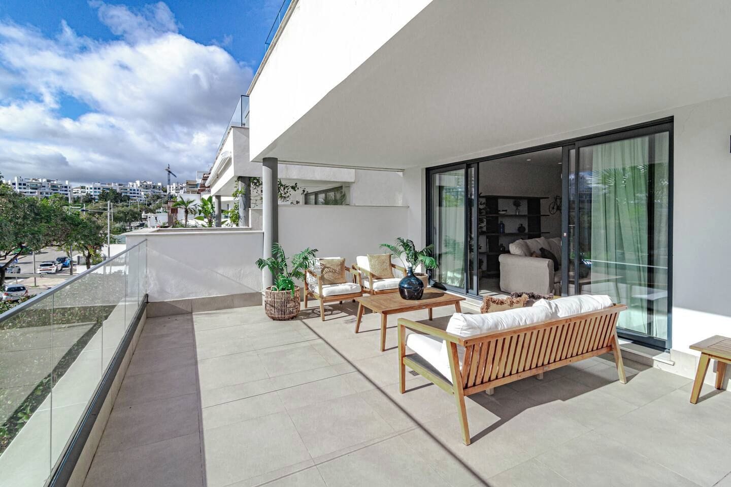 Een modern balkon met tuinmeubilair, een glazen deur naar een binnenruimte en uitzicht op de skyline.