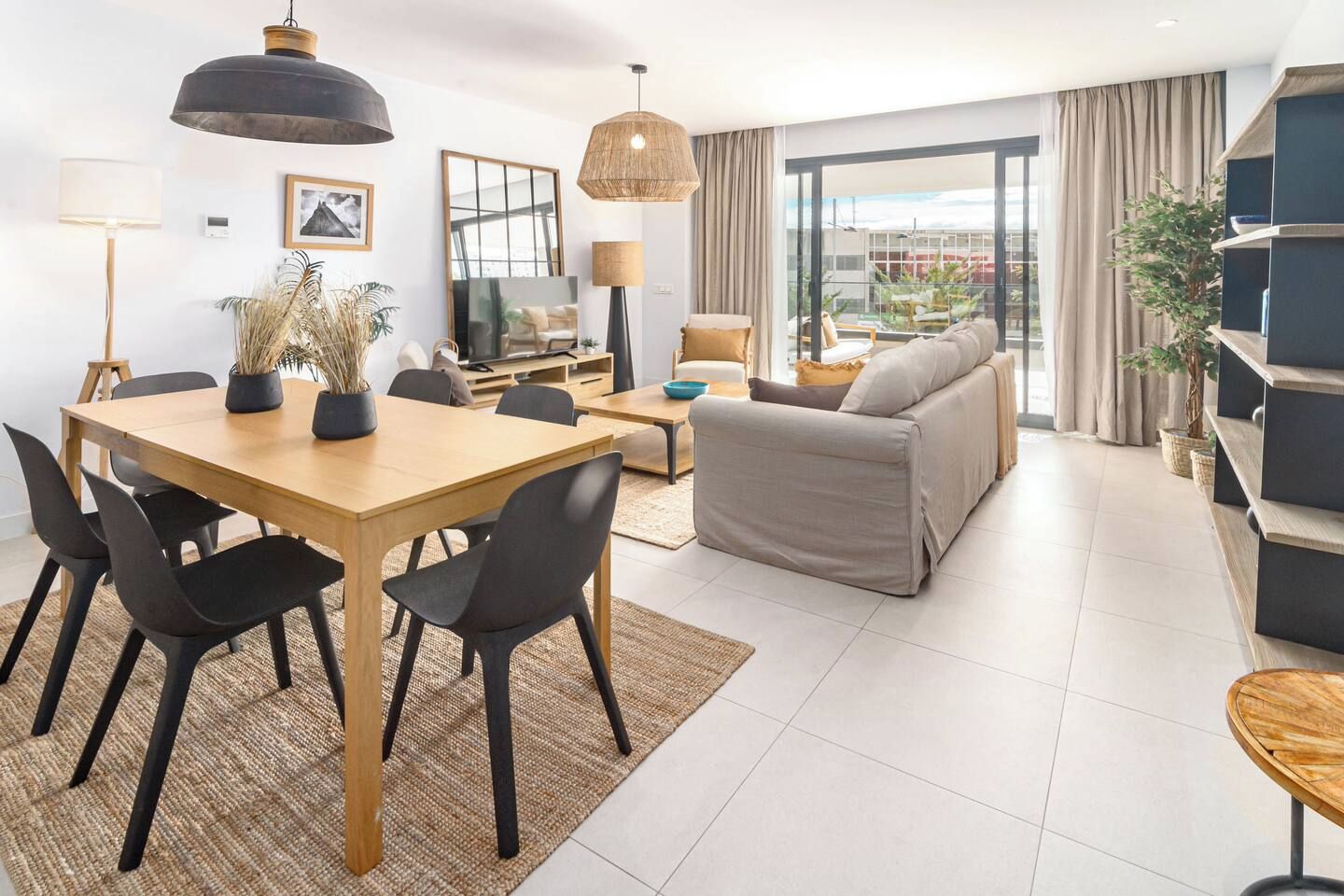 A modern living room with a dining area, a sofa, and a TV.