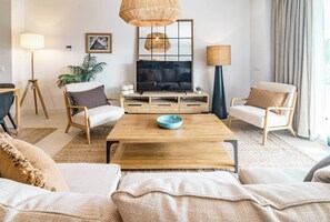 A modern living room with a wooden coffee table, two sofas, a television, and a large window with curtains. - Lme3bb - Modern Flat With a Stunning 50 m² Terrace (Estepona)