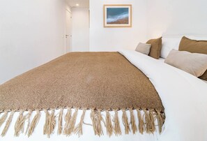 A bed with a brown woven blanket and tassels, white bedding, and a framed picture on the wall. - Lme3bb - Modern Flat With a Stunning 50 m² Terrace (Estepona)