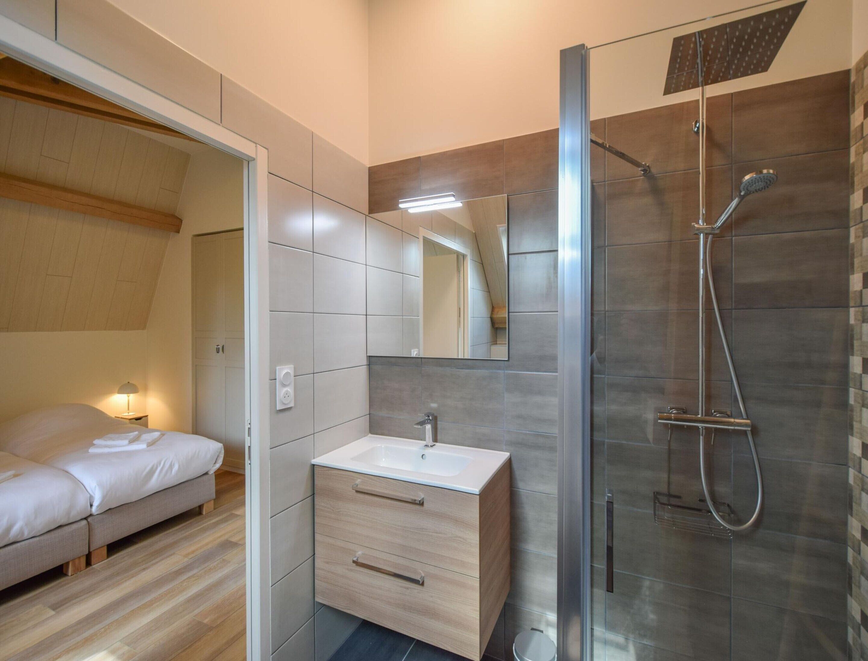 A modern bathroom with a shower, a sink, and a mirror.