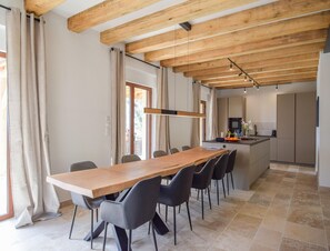 A modern kitchen with a wooden ceiling, a dining area with a long table and chairs, and a view of the outdoors. - Elegant 10-guest Villa With Pool & Castle Views (Saint-Medard-d'Excideuil)