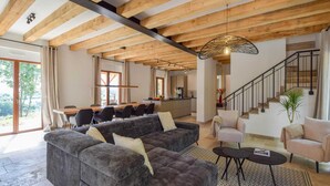 Ein geräumiger Wohnbereich mit einem großen, grauen Ecksofa, einem Couchtisch und einer Treppe, die in eine obere Ebene führt.