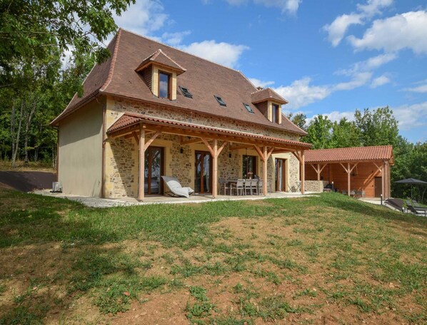 A two-story stone house with a sloped roof, a covered patio, and a small attached structure. - Elegant 10-guest Villa With Pool & Castle Views (Saint-Medard-d'Excideuil)