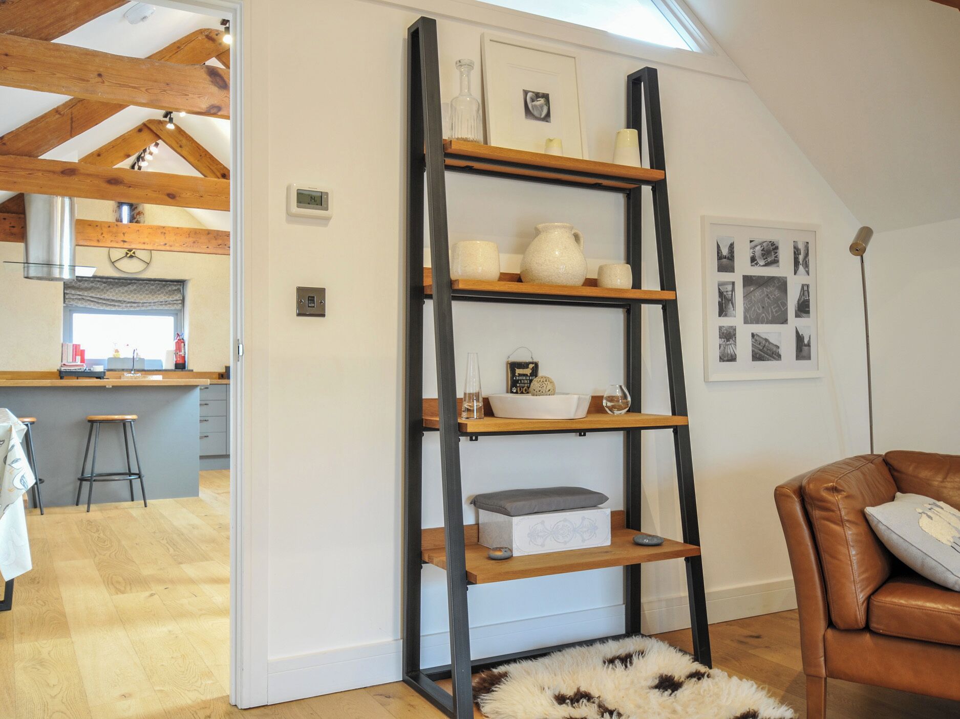 Eine moderne Küche mit Holzbalken, einer integrierten Bar und einem Schlafzimmer im oberen Bereich, erreichbar durch eine Leitertreppe.