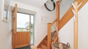 A wooden staircase with a basket and a wooden door leading to a balcony. - The Dairy (Holsworthy)