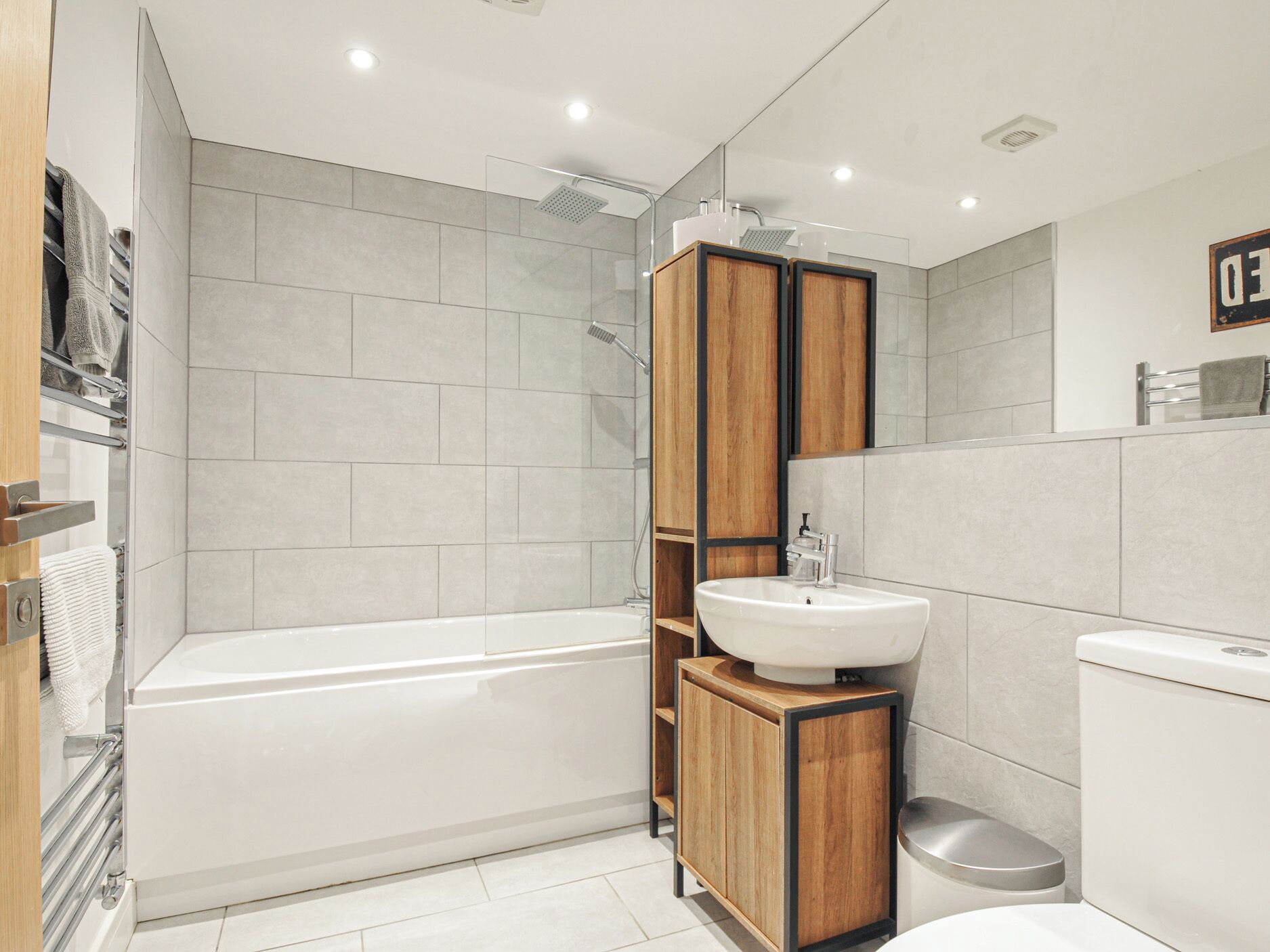 A modern bathroom with a bathtub, a wooden vanity with a sink, and a toilet.