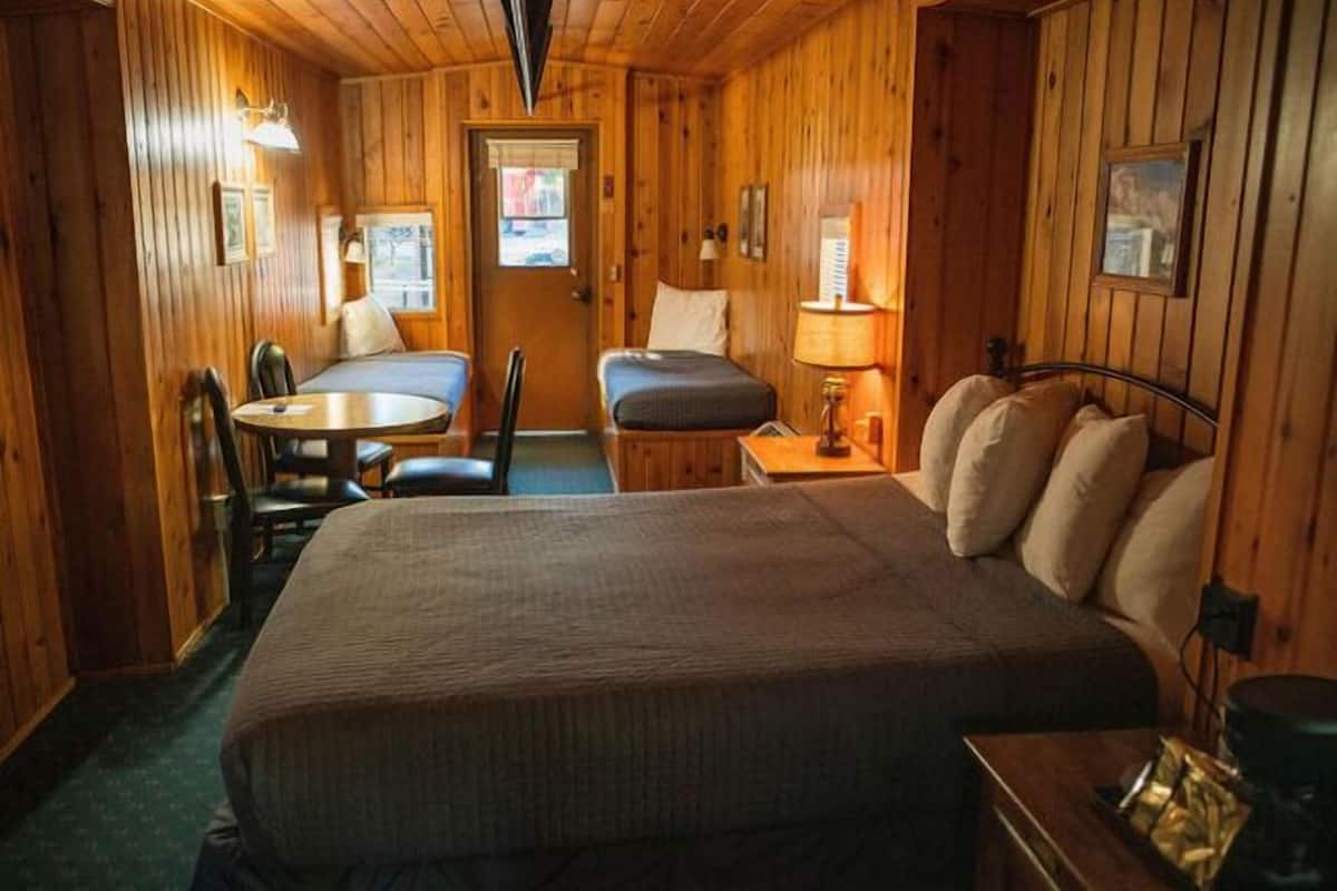 Ein holzgetäfeltes Zimmer im Chalet-Stil mit einem großen Bett, einem kleinen Tisch, einem Sessel und einem Schreibtisch.