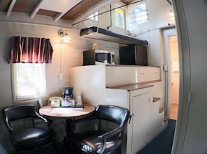 A compact kitchenette with a microwave, a coffee maker, and a small table with two chairs. - Jubilee Railroad Wilderness Lodge (Dunsmuir)
