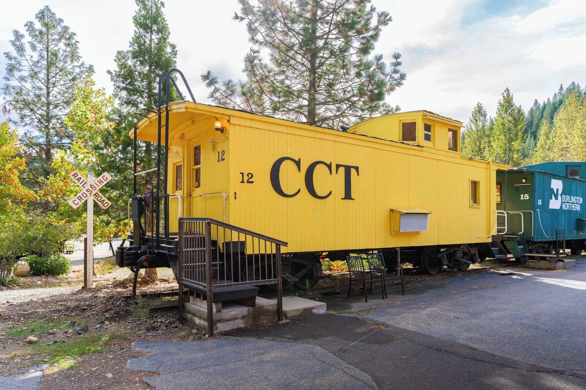 Ein gelber Waggon mit der Aufschrift 'CCT' und der Nummer '12', abgestellt auf Gleisen, mit Bäumen im Hintergrund.