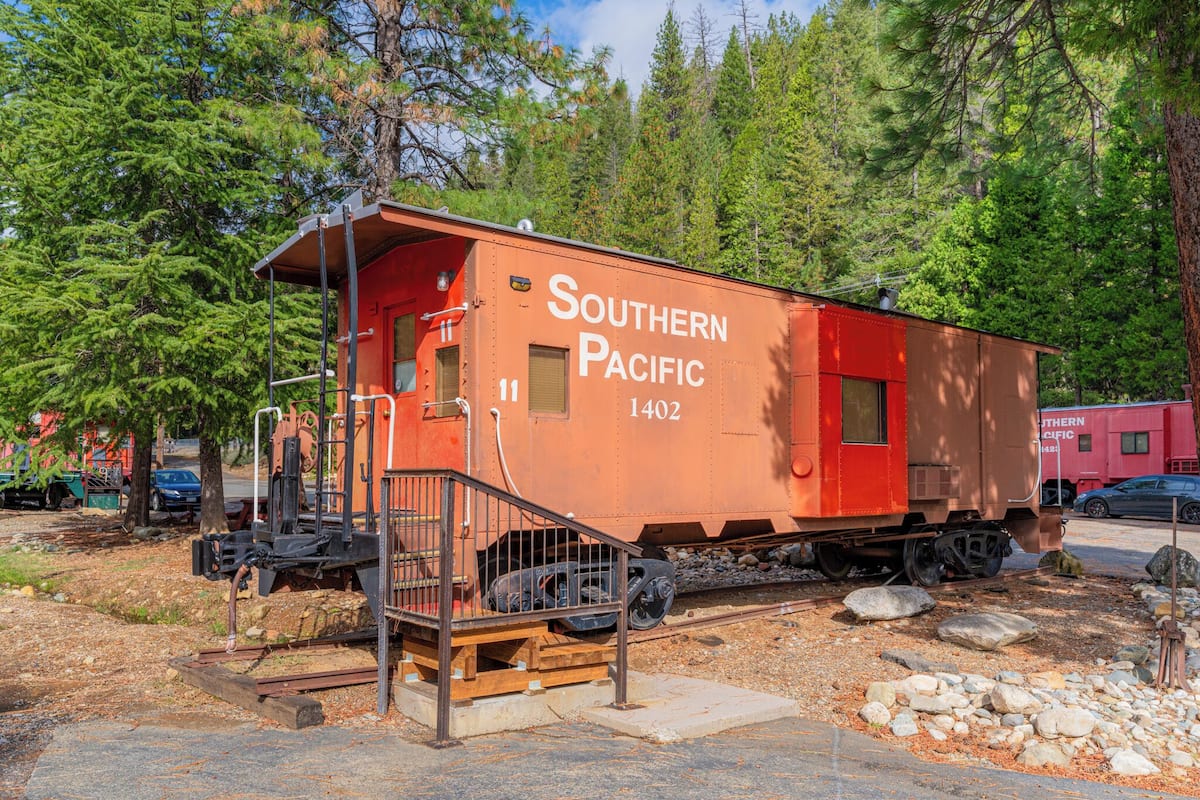 Ein stehender Güterwagen der Southern Pacific, Nummer 1402, mit einer kleinen Plattform und Treppe, umgeben von Bäumen.