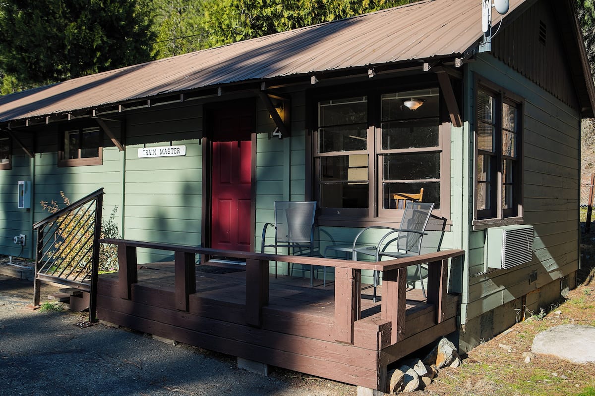 Ein kleines Gebäude mit einer Veranda, einer roten Tür und einem Schild mit der Aufschrift 'TRAIN MASTER'.