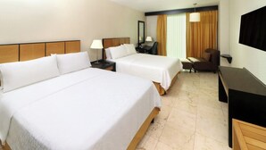 A hotel room with two beds, a desk, a chair, a TV, and a window with curtains. - Hotel Viajero Plus (Ciudad del Carmen)