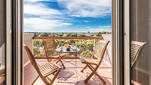 Un balcón con una mesa para dos, sillas y vistas de la ciudad.