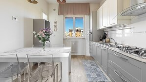 Una cocina moderna con una isla central, gabinetes grises y un ventanal con vistas a edificios.