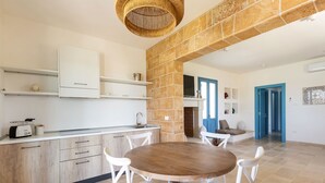 Una cucina moderna con mobili bianchi, un tavolo rotondo in legno e sedie bianche.