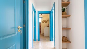 Un corridoio con porte blu e una parete bianca con mensole.