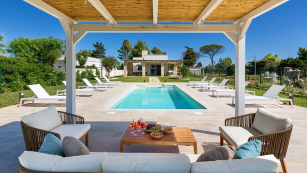 Un'area esterna coperta con piscina, sedie a sdraio e un tavolo con snack e bevande.