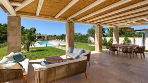 Patio esterno con piscina, mobili in vimini e vista diretta sulla zona della piscina.