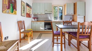 Cozinha com armários verde-claros, uma mesa de jantar com cadeiras e obras de arte nas paredes.