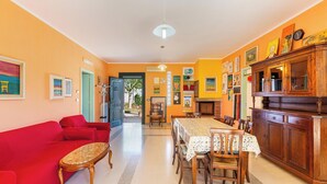 Uma sala de estar espaçosa com um sofá vermelho, uma mesa de jantar com cadeiras e um armário de madeira.