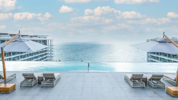 A poolside area with lounge chairs and umbrellas, overlooking a calm sea and a clear sky. - 2-BR Garza Blanca Exclusive Resort for New Year's 2027 1 full week (PUNTA SAM)