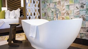 A modern bathroom with a freestanding bathtub, a wooden side table, and a patterned tile wall. - 2-BR Garza Blanca Exclusive Resort for New Year's 2027 1 full week (PUNTA SAM)
