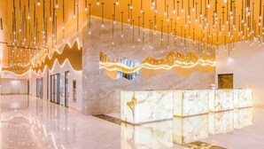Eine moderne Hotellobby mit einer Marmor-Rezeption, hängenden Leuchten und einem glänzenden Boden.