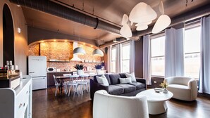 Ein modernes Wohnzimmer mit einer Couch, einem Couchtisch und einem Essbereich mit Stühlen sowie einer Küche im Hintergrund.