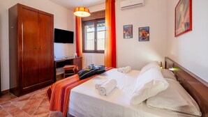 Une chambre d’hôtel équipée d’un lit, d’un bureau, d’une armoire et d’un téléviseur.