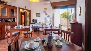 Un coin repas avec des meubles en bois, une table dressée pour quatre personnes et une vue sur l’extérieur.