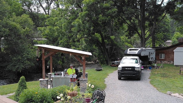 A gravel driveway leading to a house with a covered patio and a garden. - Full 30 amp hookup on beautiful Deep Creek (Bryson City)