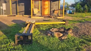 A rustic cabin with a wooden porch, a small outdoor seating area, and a gravel driveway. - Relaxing Fun Bunk house 2 (Weyerhaeuser)