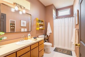 A bathroom with a wooden vanity, a large mirror, a toilet, and a shower curtain.