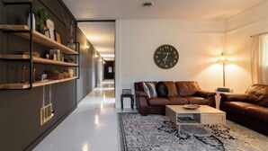 Een moderne woonkamer met een bank, salontafel en een grote wandklok.