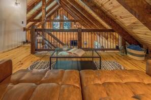 Un acogedor espacio tipo loft con una mesa de centro de cristal, un sofá de cuero y vistas a una escalera de madera.