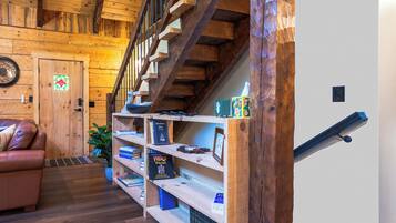 Una escalera de madera con barandilla, una estantería con libros y una puerta con un panel de vidrio decorativo.