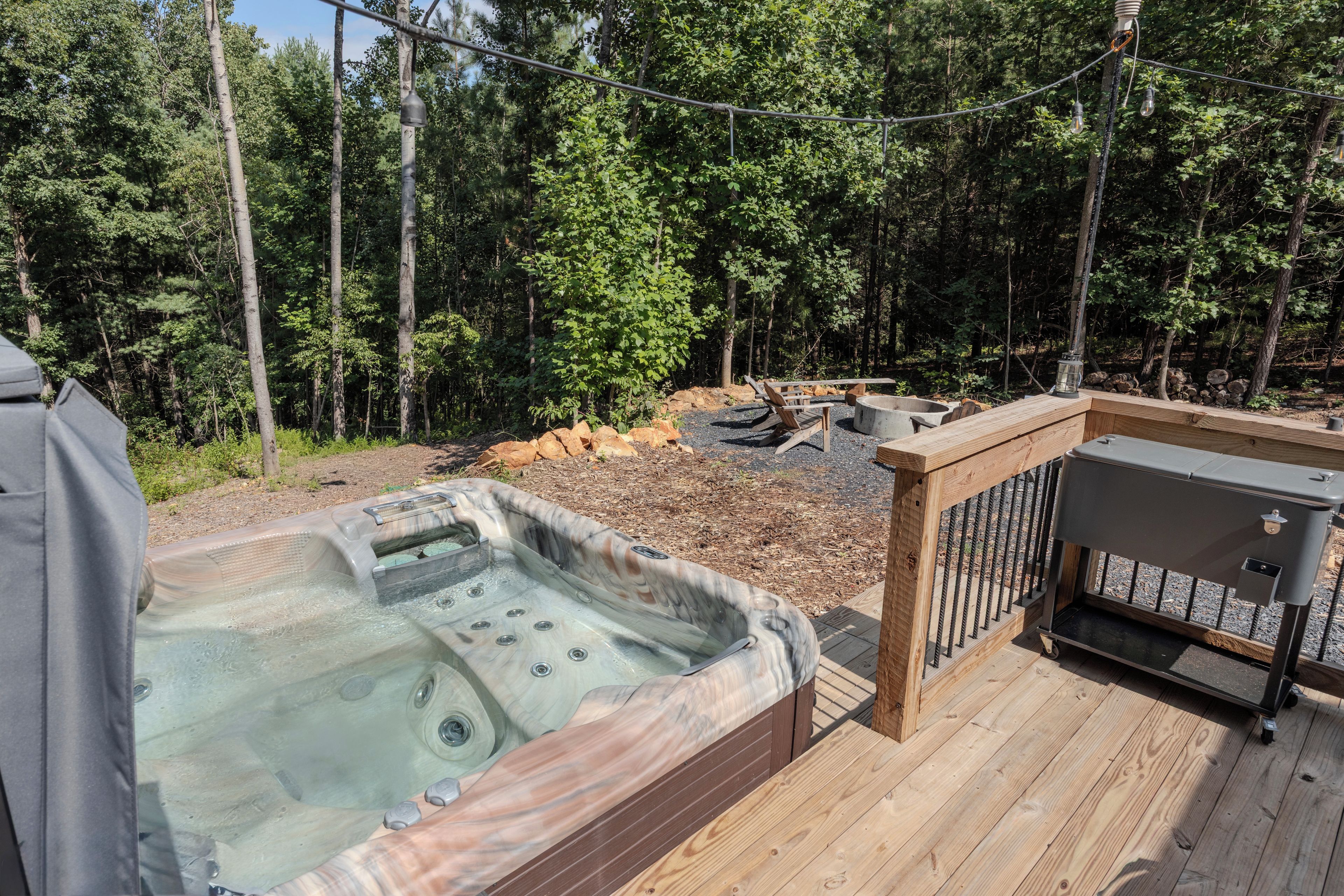 A hot tub on a wooden deck with a view of a forest.