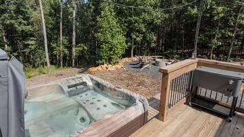 A hot tub on a wooden deck with a view of a forest.