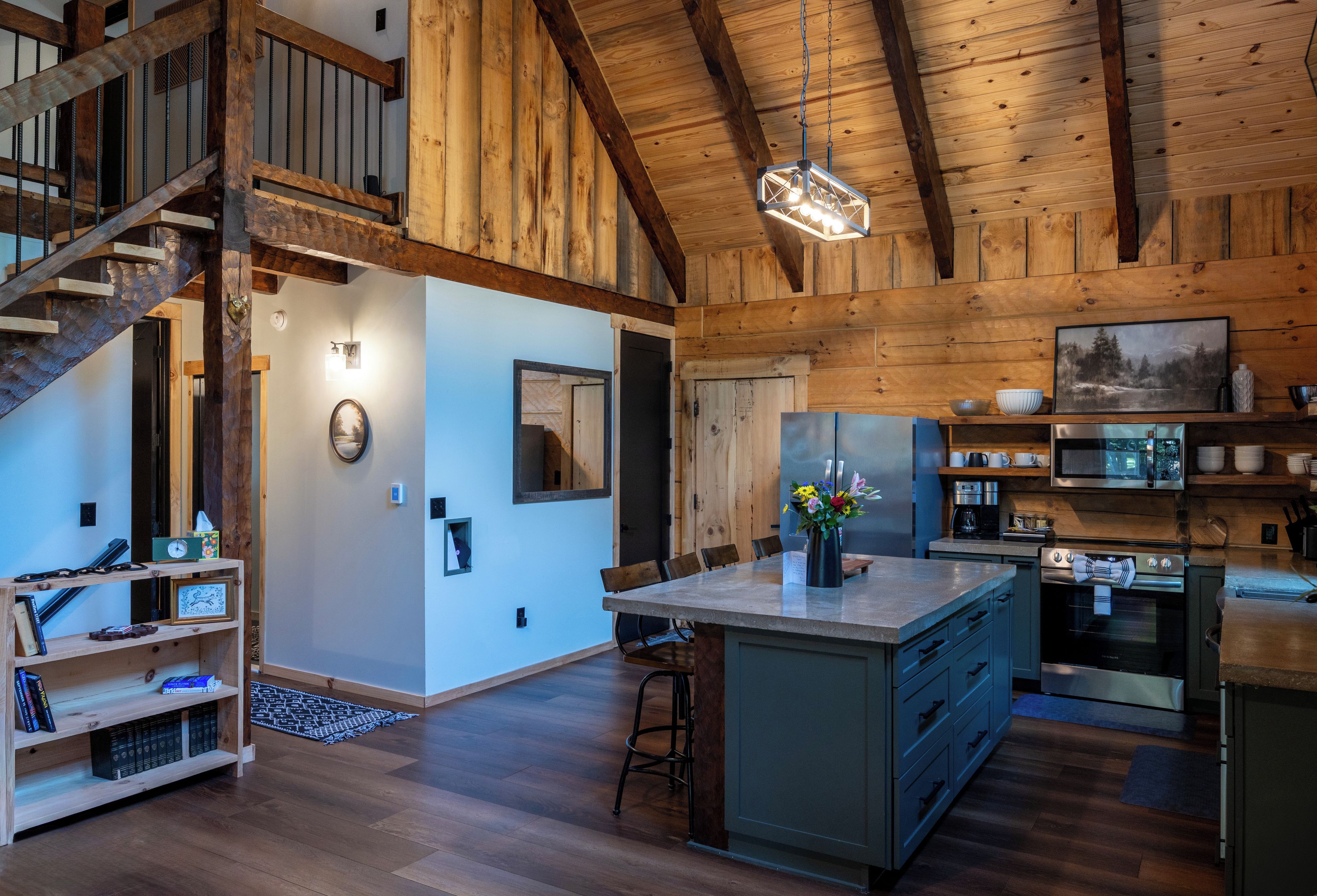 A spacious kitchen with wooden beams, a dining area with a large island, and a staircase leading to an upper level.