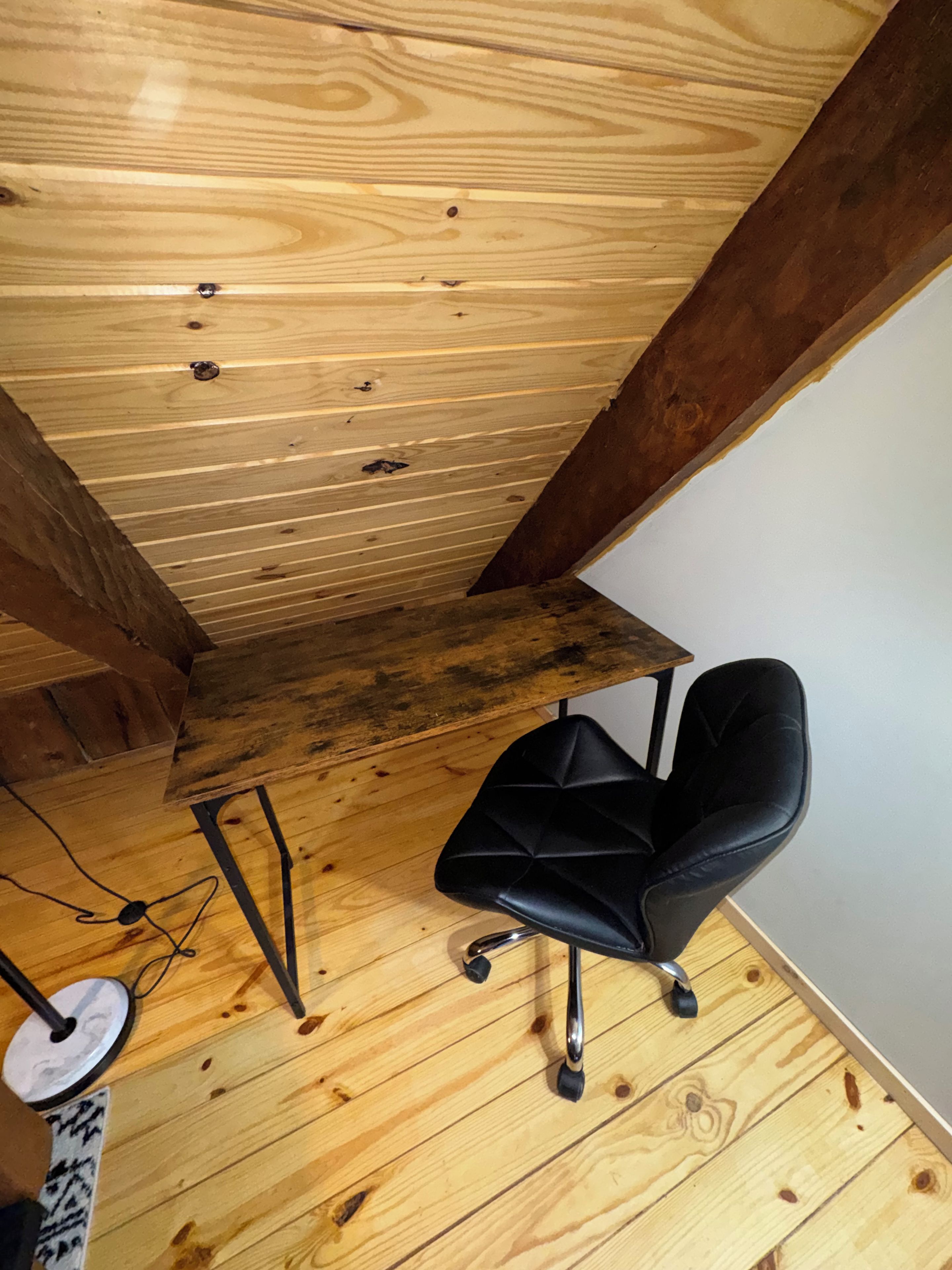 A wooden ceiling with visible beams and a black office chair.