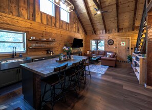 Interior de una cabaña de madera con cocina, comedor y sala de estar.