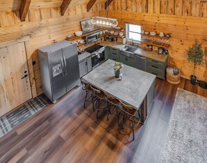Une cuisine compacte équipée d’un réfrigérateur, d’une cuisinière, d’un four à micro-ondes et d’un évier. On y trouve une table à manger avec des chaises et une petite plante en pot.
