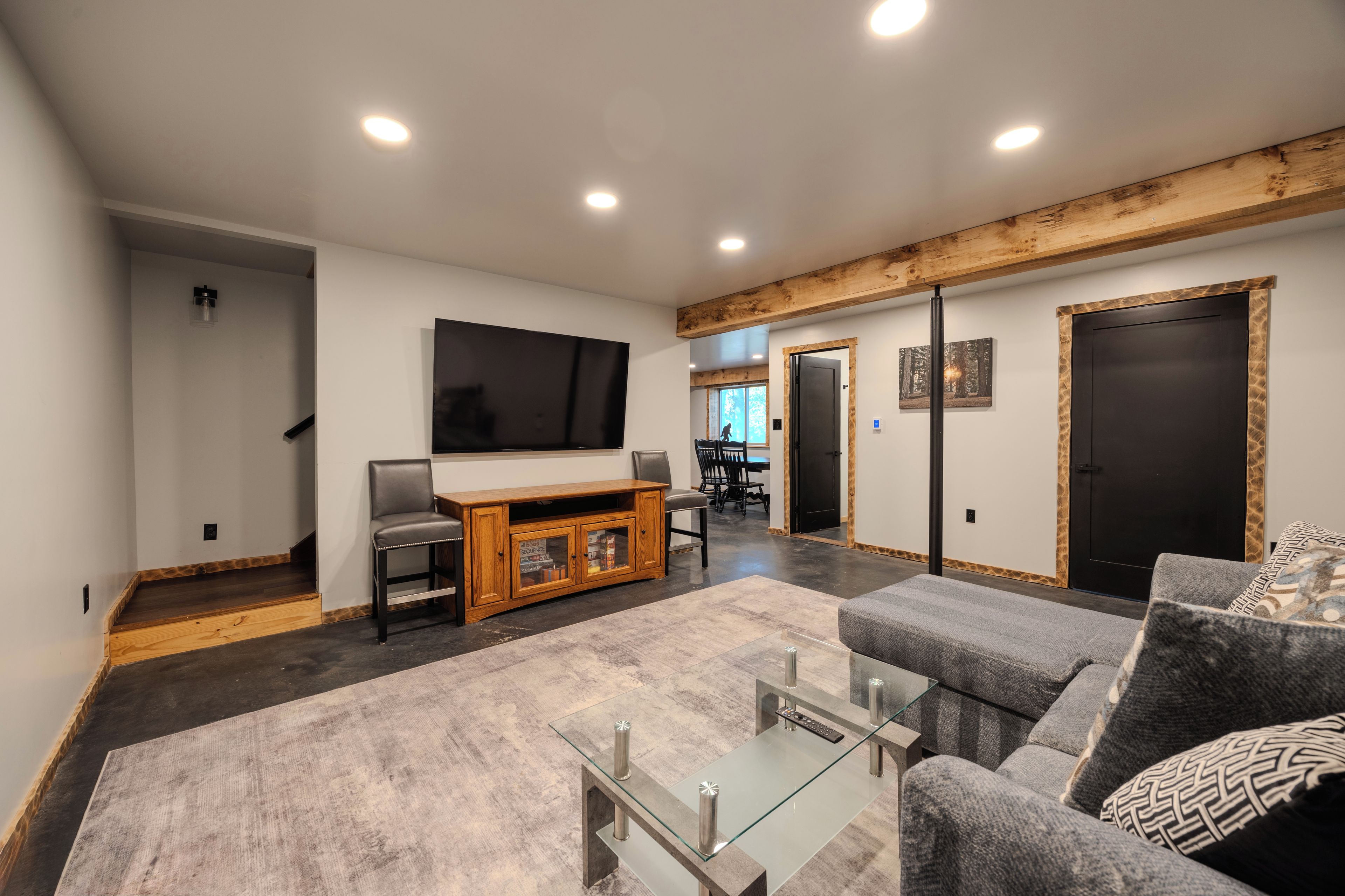 A modern living room with a flat-screen TV, a sofa, a glass coffee table, and a wooden entertainment unit.
