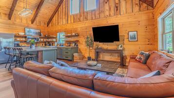 A cozy cabin interior with a wooden interior, a leather sofa, a dining area, and a kitchen.